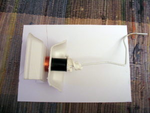 The complete coil winder with a coil. The tissue paper keeps the coat hanger jammed inside the film canister.